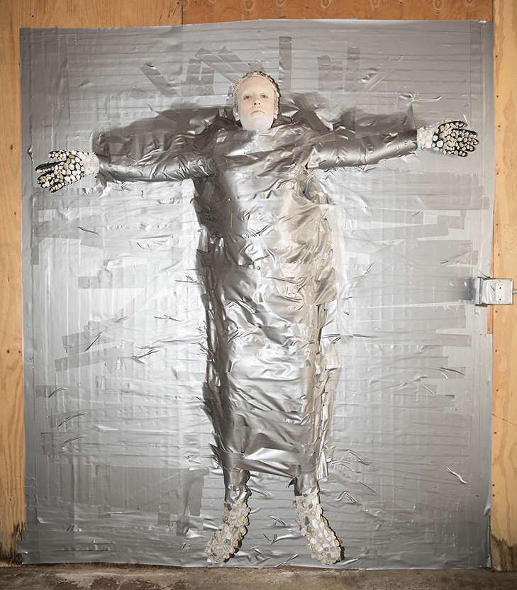Photograph of Jesse duct taped to a wooden wall.